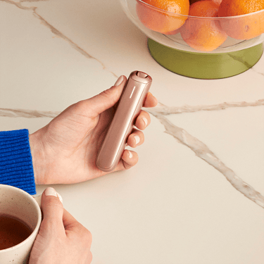 Hand holding the Ploom AURA Rose Gold.