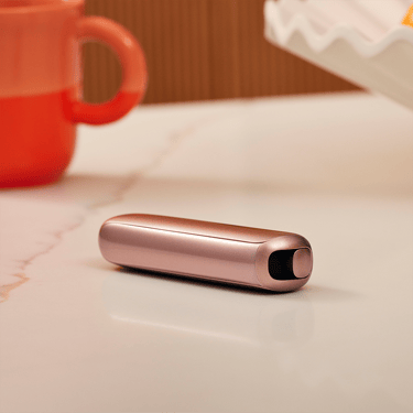 Ploom AURA Rose Gold device on a table during a coffee break.