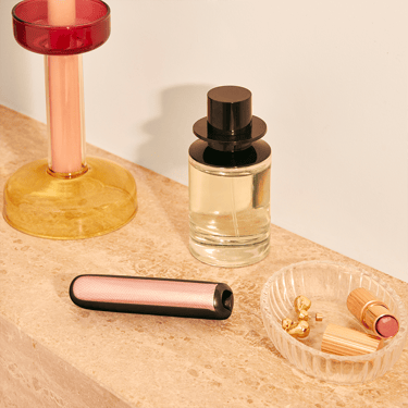 Ploom AURA front panels with Rose Gold Augmented Pattern placed on a dressing table.