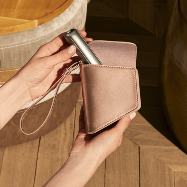 Hand taking a Ploom AURA device out of the Ploom Duo Carry Case Rose Gold