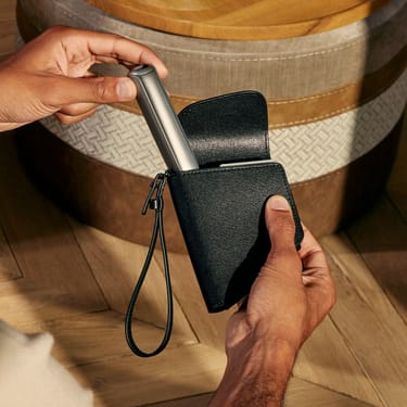 Hand taking a Ploom AURA device out of the Ploom Duo Carry Case Jet Black