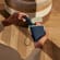 Hand taking a Ploom AURA Navy Blue  device out of the Ploom Duo Carry Case Denim Leather Fusion