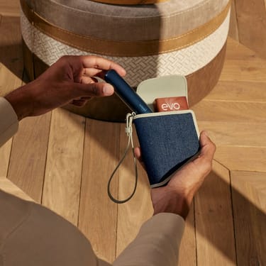 Hand taking a Ploom AURA Navy Blue  device out of the Ploom Duo Carry Case Denim Leather Fusion
