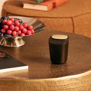 حاملة أعواد التبغ الكبيرة من Ploom موضوعة على طاولة بنية.