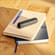 Ploom device with Jet Black Back Cover on top of a stack of notebooks
