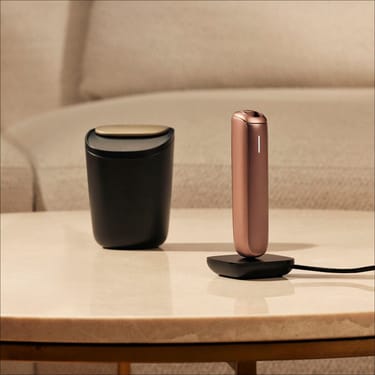 حاملة أعواد التبغ الكبيرة من Ploom بجانب جهاز Ploom AURA أثناء الشحن.