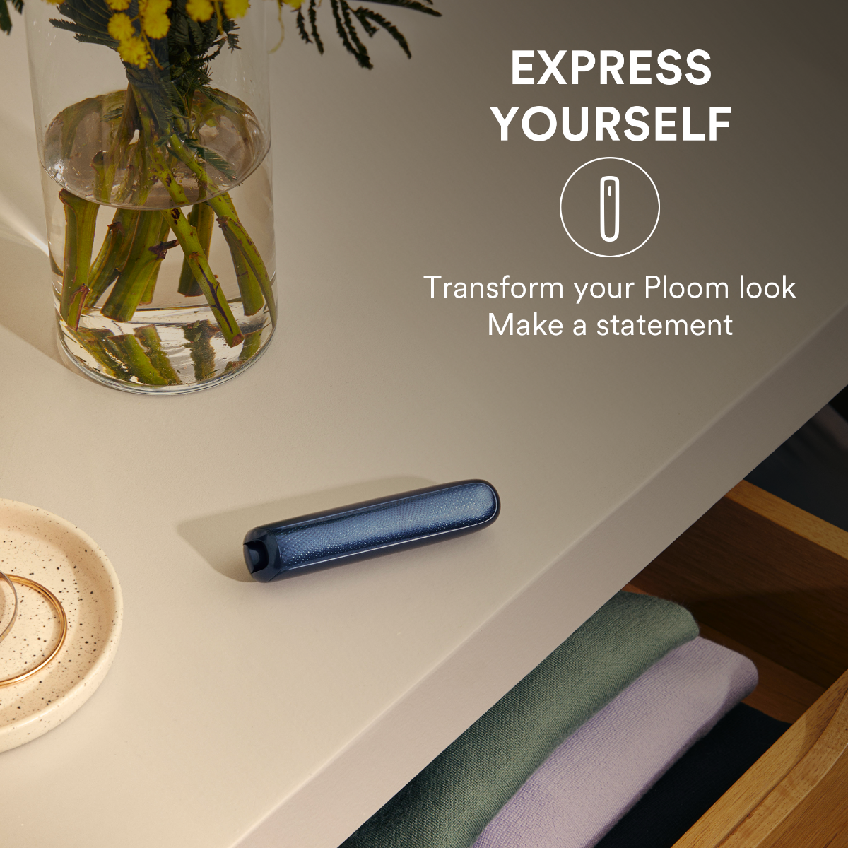 Ploom AURA device placed on a table beside a vase-8